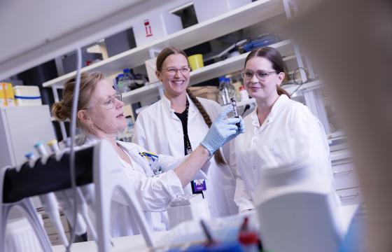 KOlme naista tutkivat näytteitä laboratoriossa valkoiset takit päällään