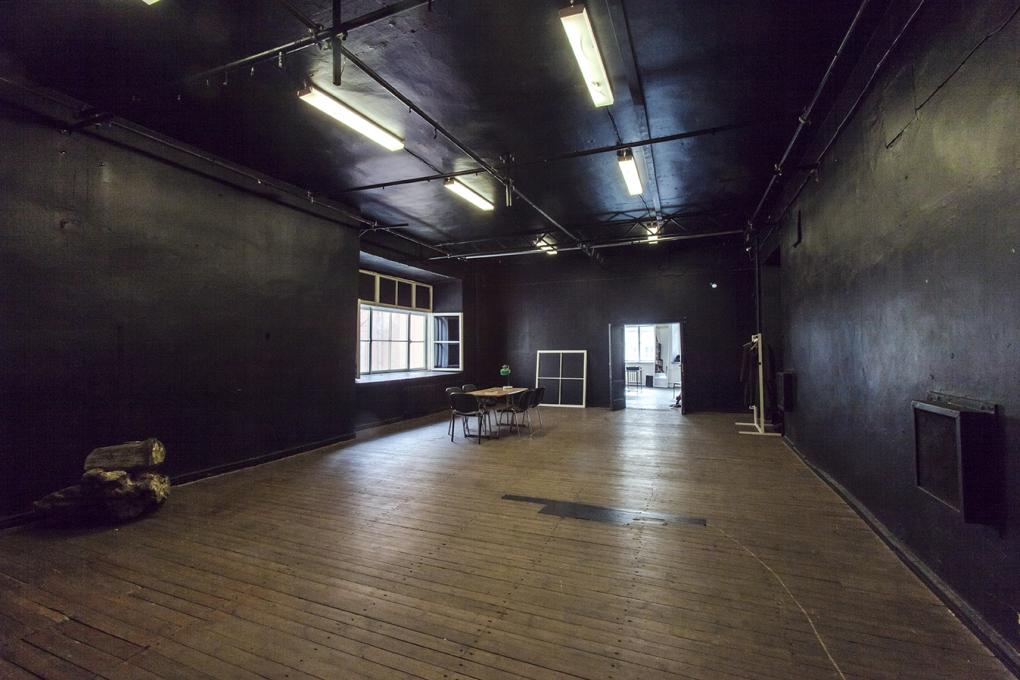 Suuri huone, jossa on puinen lattia ja mustat seinät