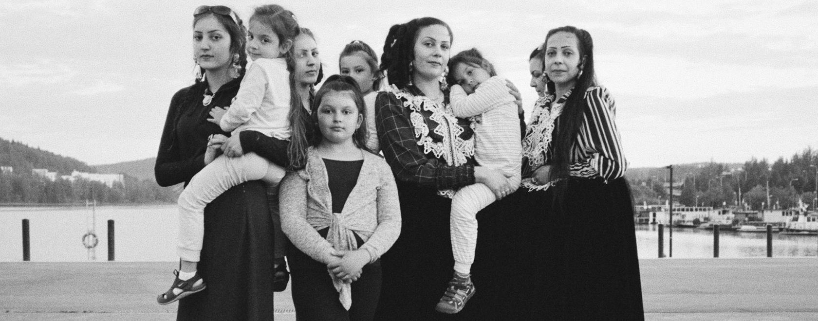 Romaninaisia ja lapsia seisomassa ryhmässä katsoen kameraan