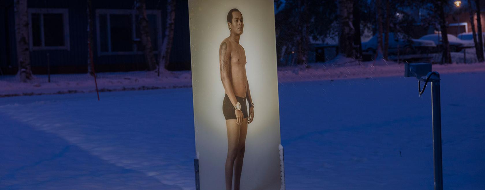 Aki Roukala: Contemporaries, Pudasjärvi. The work consists of eight life-size portraits on glass panels placed in different locations in the centre of the small municipality.