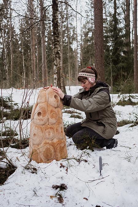 Nainen tekee puista veistossa lumisessa metsässä.