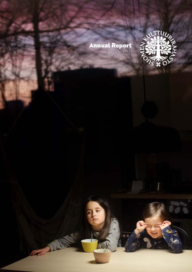 Two children sitting at dining table. Dark background.