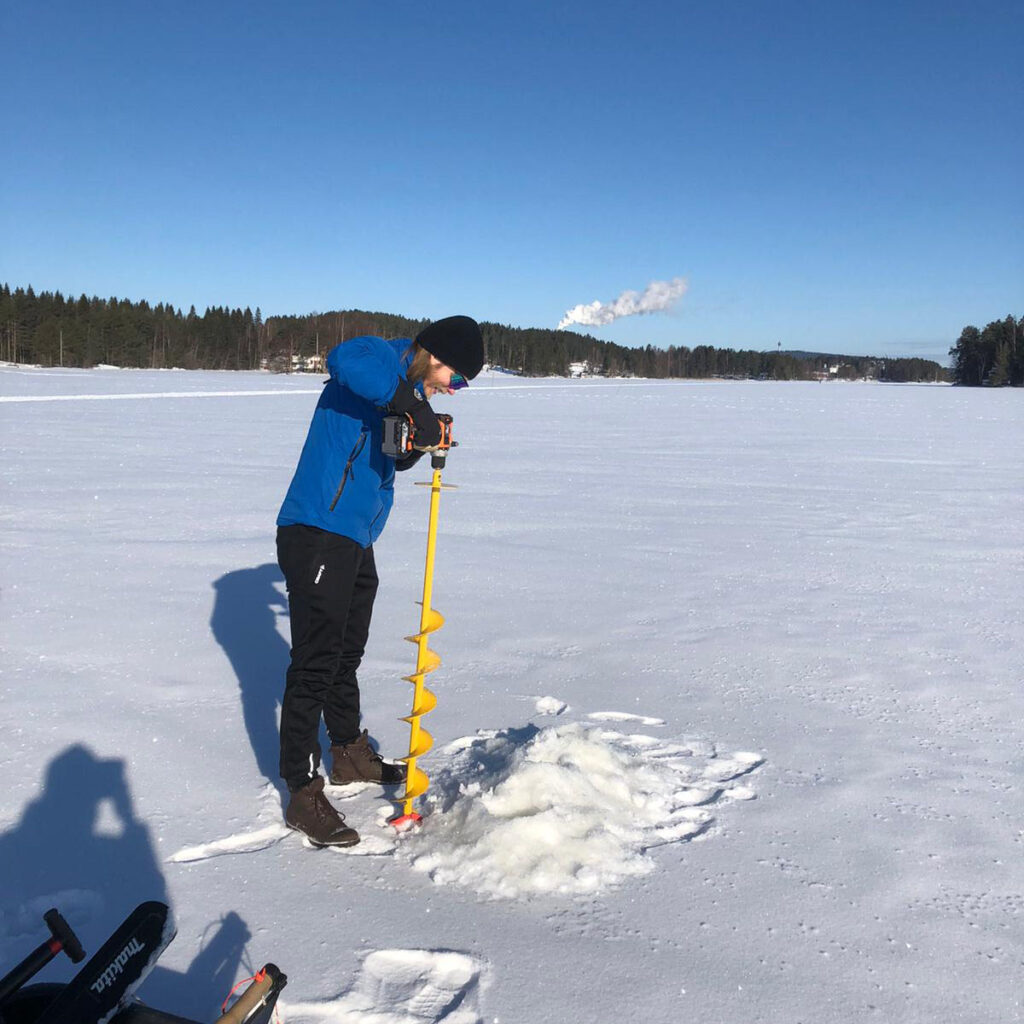 Mies kairaamassa jäätä lumisessa maisemassa
