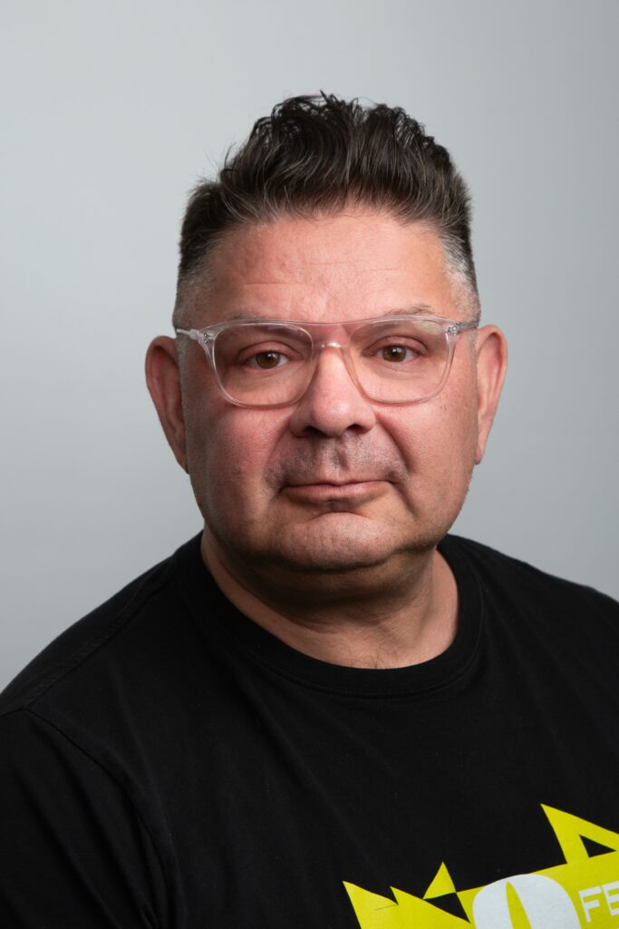 Kavokuva lyhythiuksisesta miehestä silmälasit ja musta t-paita päällä.