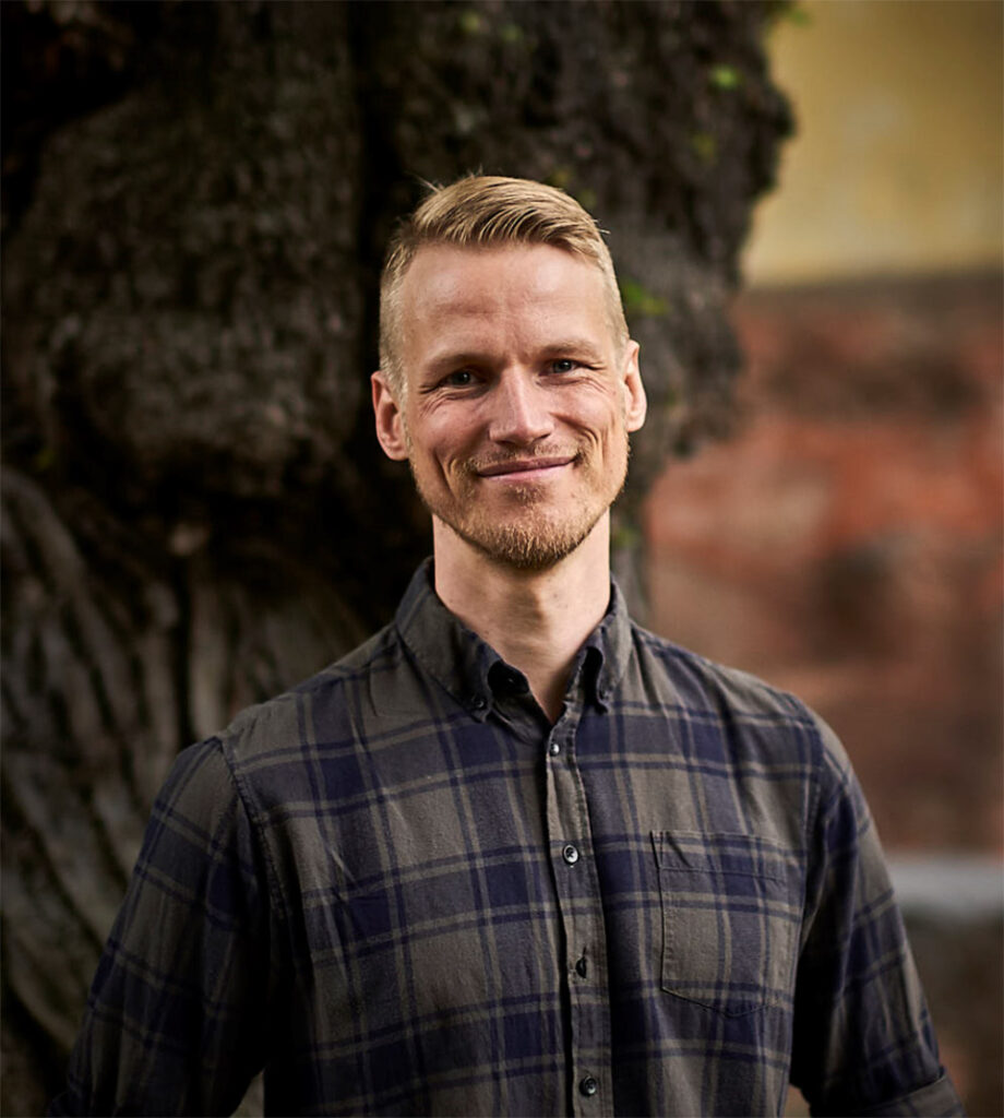 Vaaleahiuksinen mies ruudullisessa flanellipaidassa.