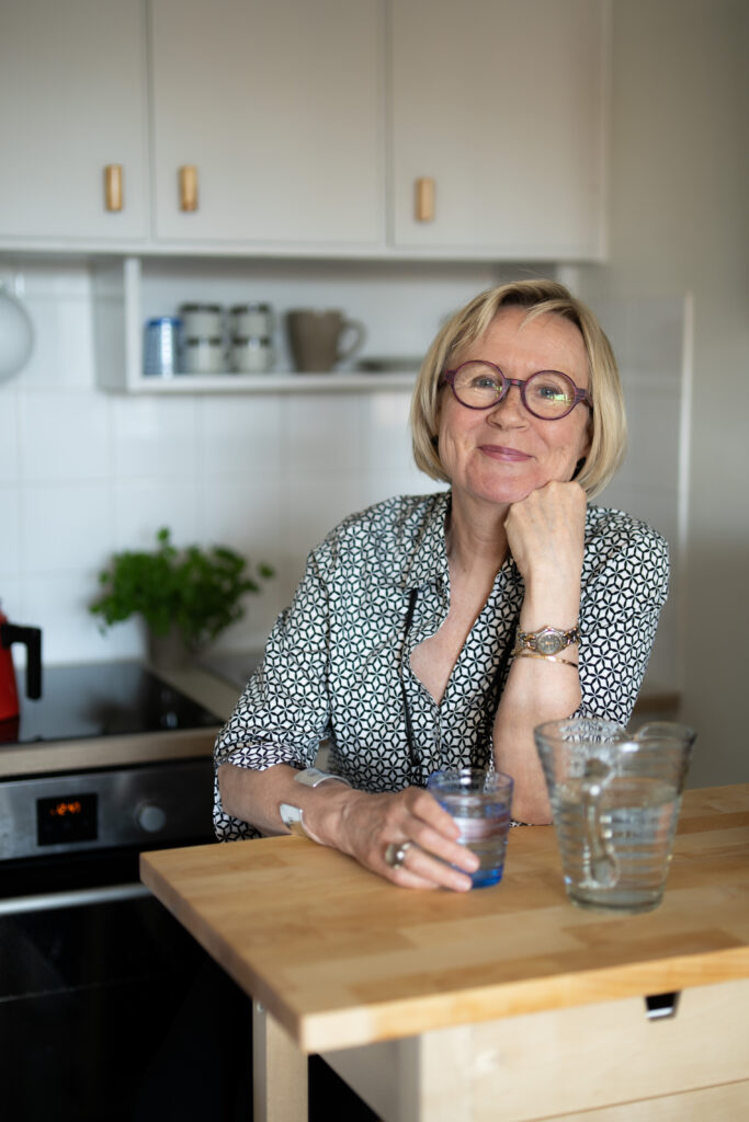 Nainen nojaa keittiössä puiseen saarekkeeseen.