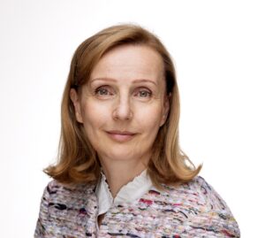 Vaaleahiuksinen nainen, jolla on jakku päällään. Kuva on otettu hartioista ylöspäin, tausta on valkoinen.
